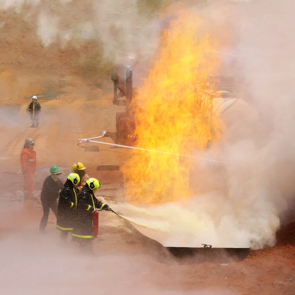 Brigada de incêndio com EPIs combatendo fogo em área industrial NR-20